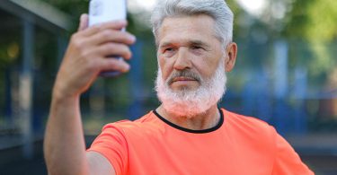 serious aged man taking selfie on smartphone