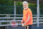cheerful senior man playing tennis on street