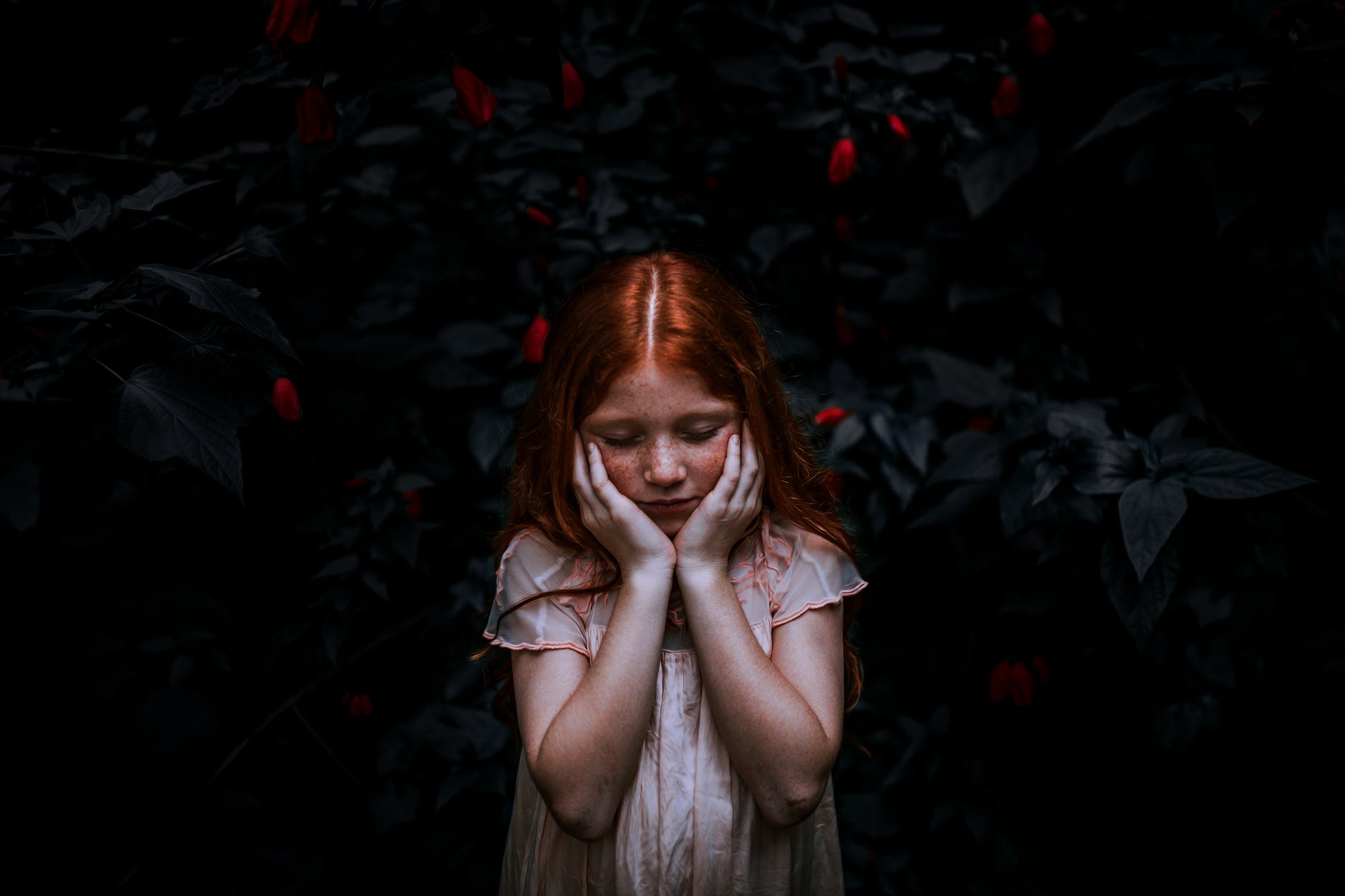 red haired girl standing near plant