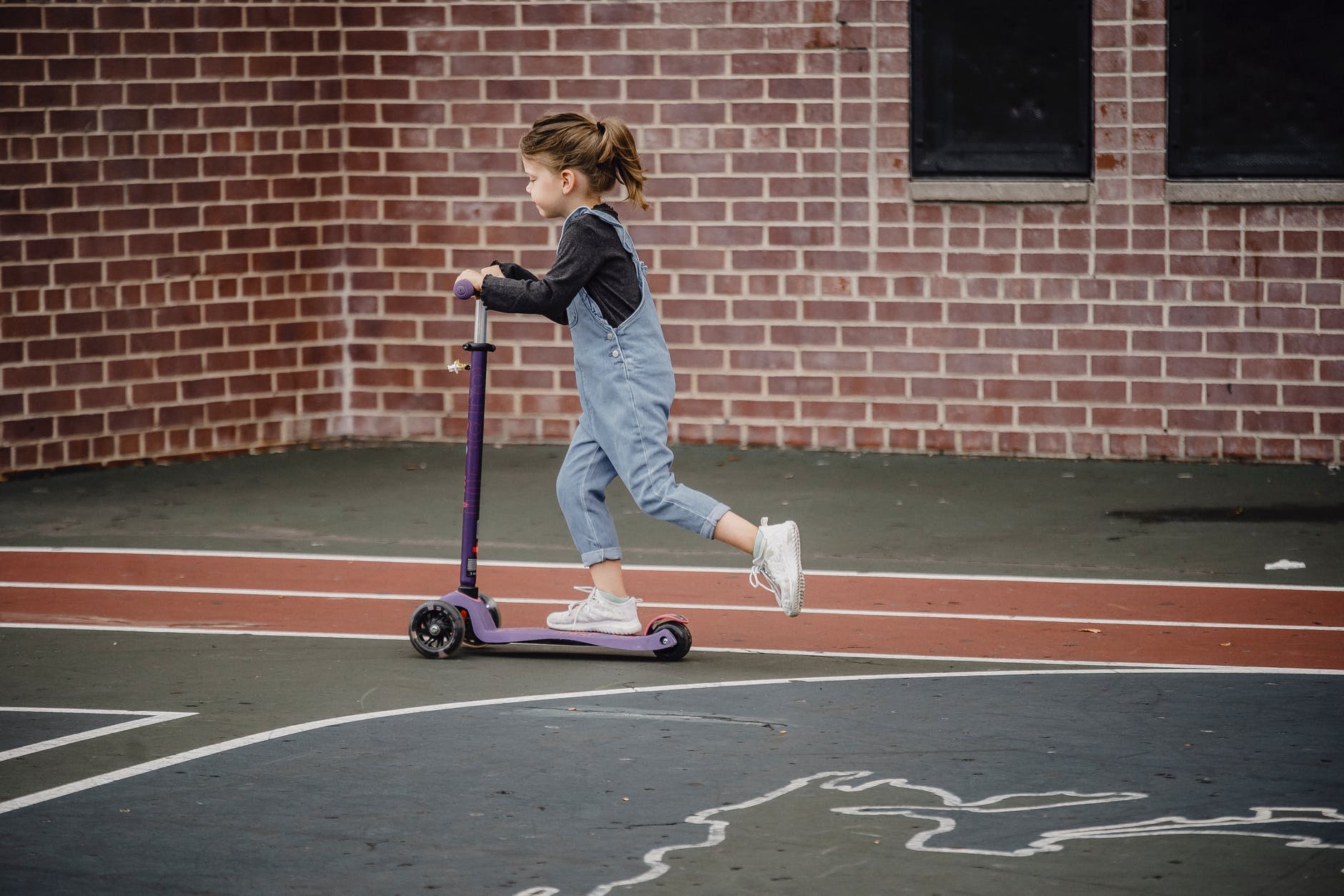 little girl riding scooter on stadium