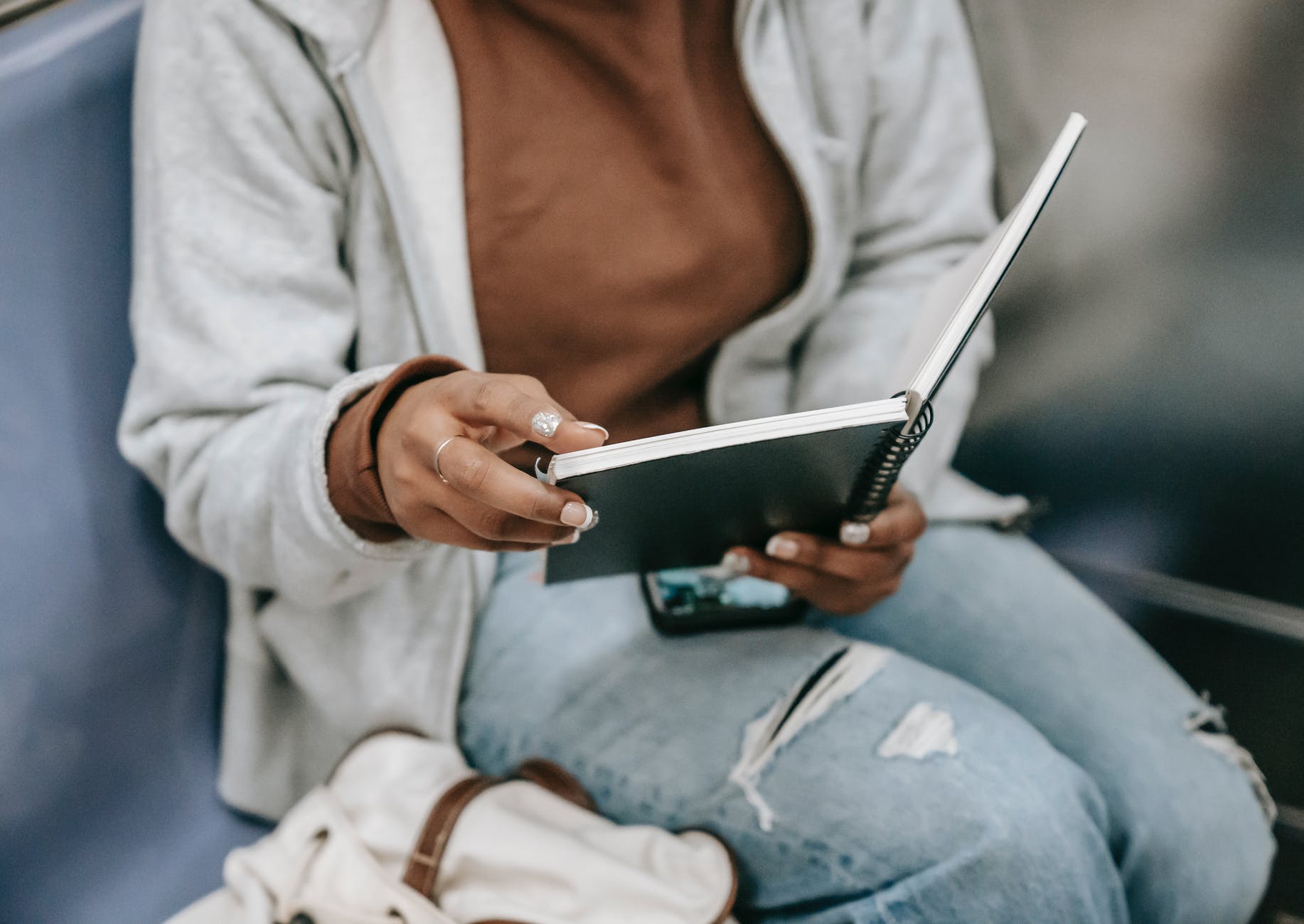 faceless ethnic female sitting with notebook in train