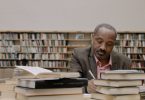 man in gray suit jacket sitting beside books