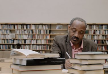 man in gray suit jacket sitting beside books