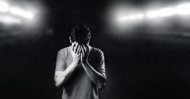 monochrome photo of man covering his face
