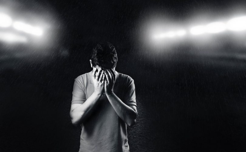 monochrome photo of man covering his face