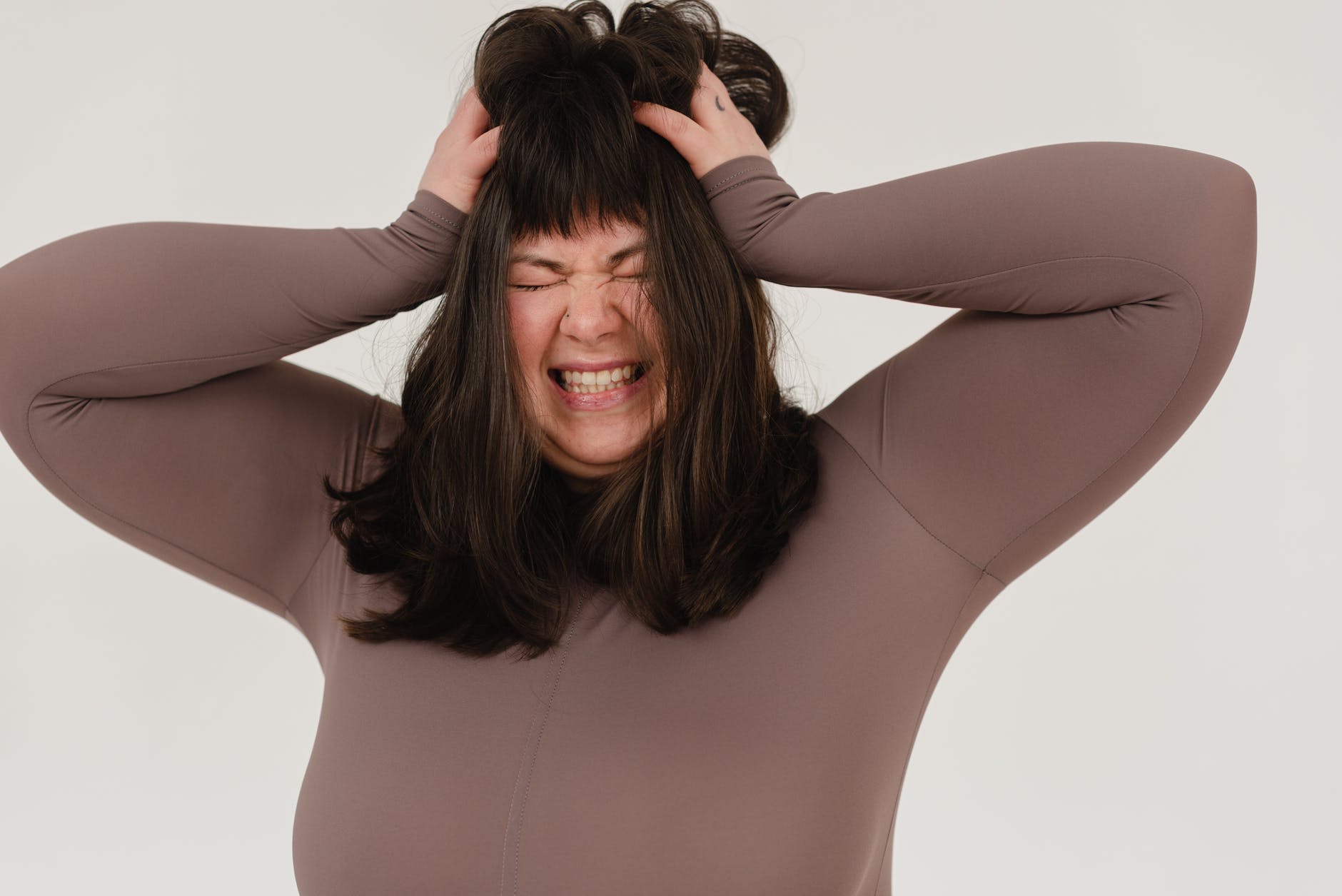 young obese woman rumpling hair with closed eyes in white studio
