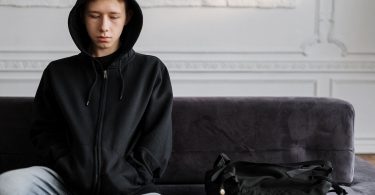 man in black zip up hoodie sitting on purple sofa