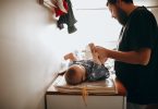 young father changing diaper of newborn baby