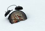 Black alarm clock on snow covered ground