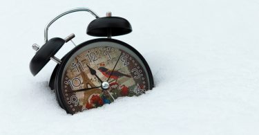 Black alarm clock on snow covered ground