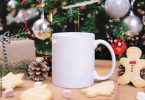 White ceramic coffee cup and christmas decoration on woon table background. mockup for creative advertising text message or promotional content.