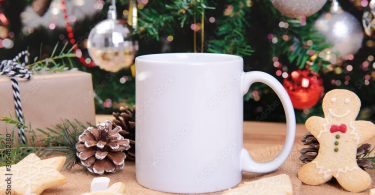 White ceramic coffee cup and christmas decoration on woon table background. mockup for creative advertising text message or promotional content.