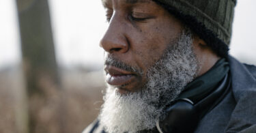 Serious bearded black man in warm clothes with closed eyes