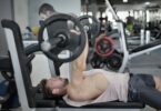 Strong sportsman doing bench press during workout in modern gym