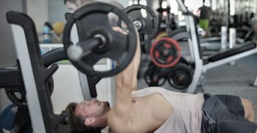 Strong sportsman doing bench press during workout in modern gym