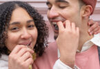 Happy young ethnic couple feeding each other with chocolates