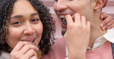 Happy young ethnic couple feeding each other with chocolates