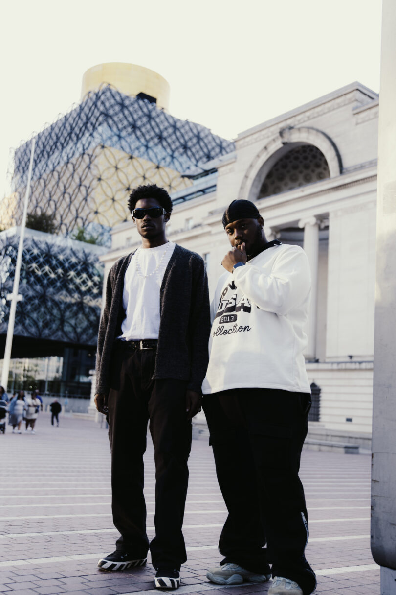 Two young men standing in a public square near library of birmingham england