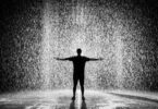 Silhouette and grayscale photography of man standing under the rain