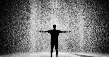 Silhouette and grayscale photography of man standing under the rain