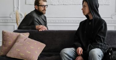 Man in black jacket sitting on couch