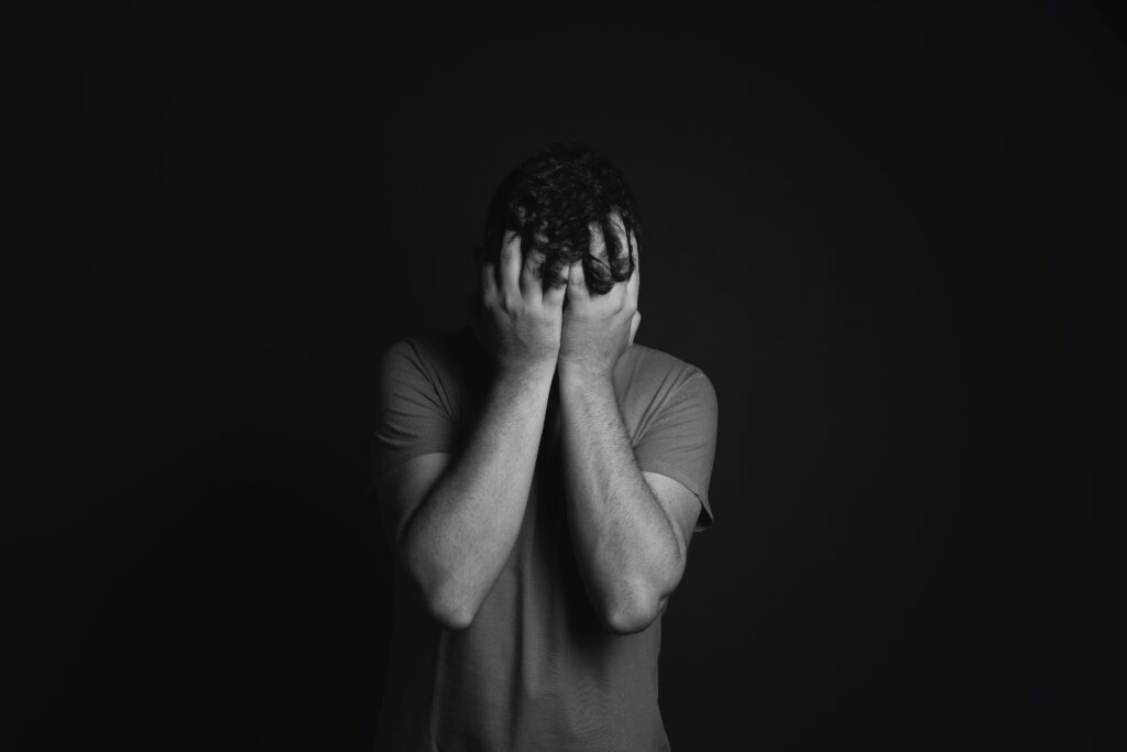 Gray scale photo of man covering face with his hands