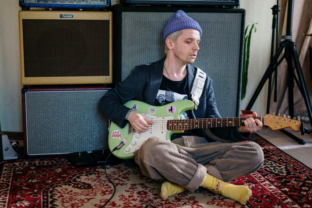 Man in black jacket playing white electric guitar