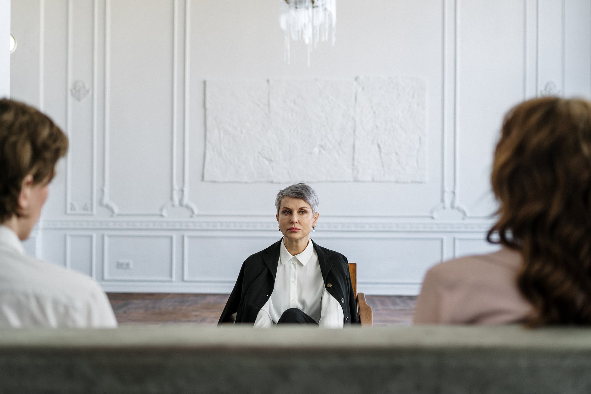 man in black suit sitting on brown couch