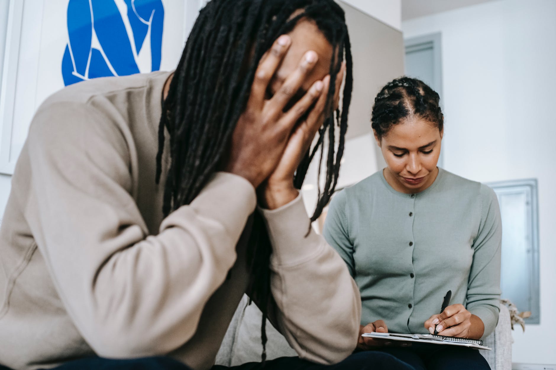 tired man sitting near female therapist writing notes